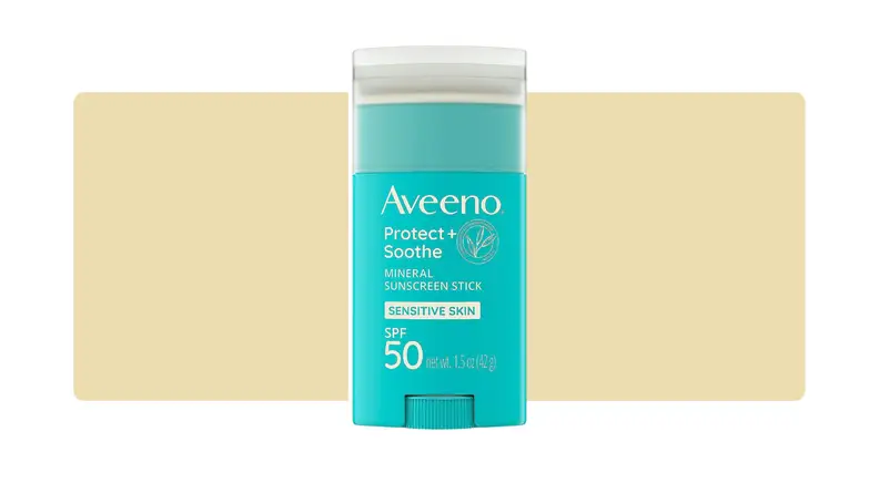 Aveeno sunscreen stick in front of a yellow background.