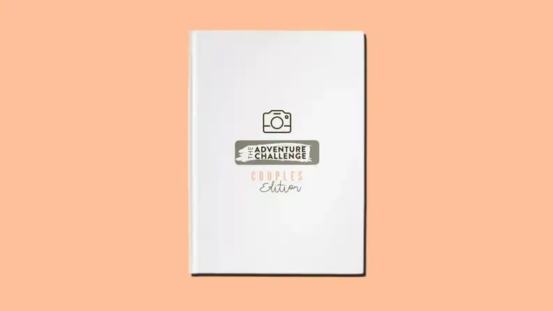 A white hardcover journal that reads The Adventure Challenge Scrapbook: Couples Edition on an orange background.