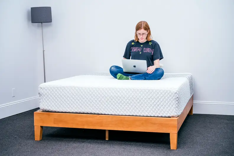 a person sits atop the Leesa hybrid working on their computer