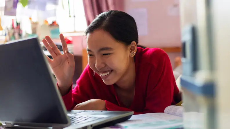 A teenager interacting with a laptop.