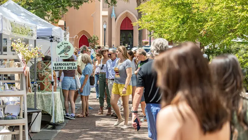 Crowd walking past a bakery stall at an outdoor market