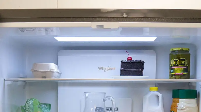 A close-up of the Whirlpool WRQA59CNKZ's crisper drawers. The fridge is fully stocked with food, and the crispers hold various fruits and vegetables.
