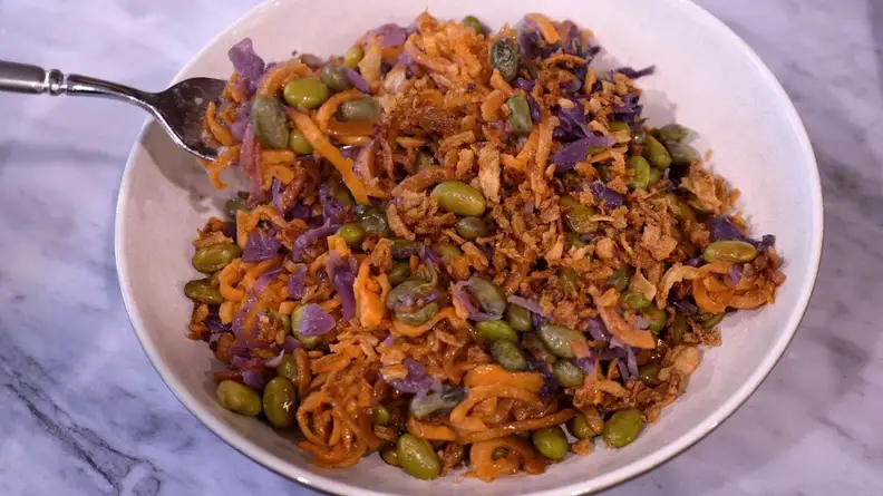 Cooked vegetables and rice inside of white bowl on countertop surface.