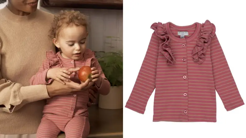 A baby wearing a ruffle-sleeved cardigan.
