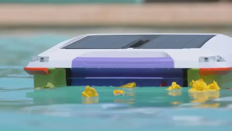 The Ariel by Solar Breeze sneaking up on some yellow flower petals that are floating on the surface of a pool.