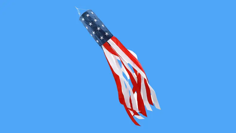 A windsock blowing in the wind against a blue background.