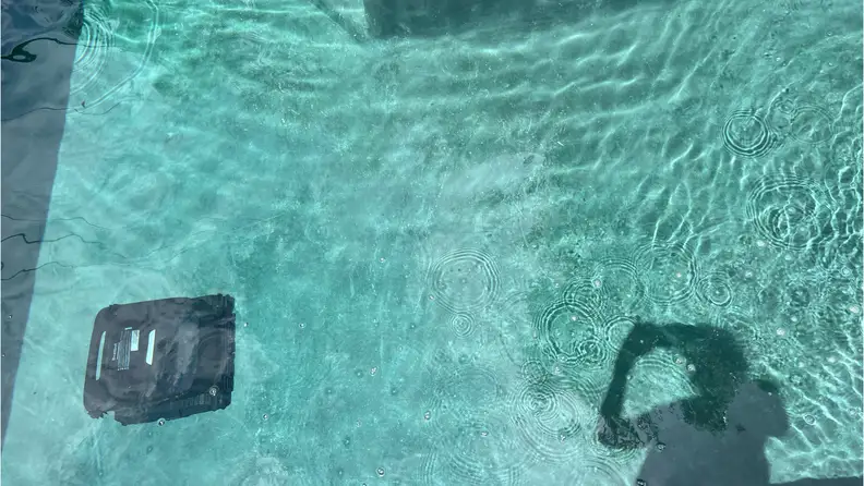 Black Beatbot Aquasense X Robot Pool Cleaner being operated in clear blue water.