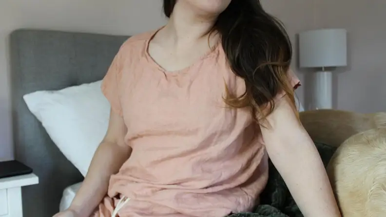 Woman sitting on the edge of the bed wearing MagicLinen pajamas