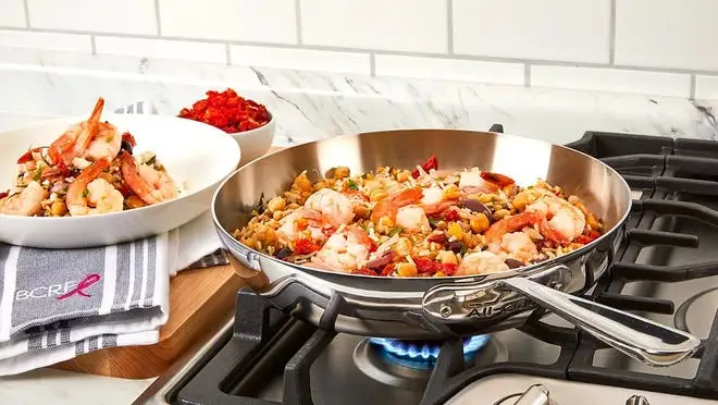 Silver skillet on cooktop eye with food inside.