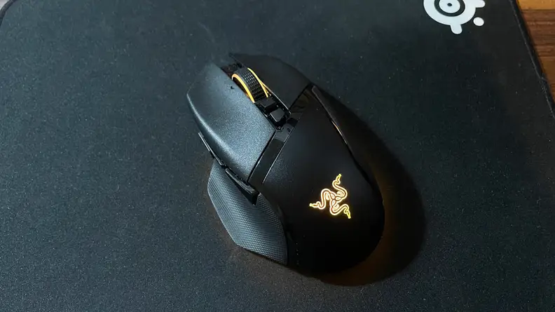The Razer Basilisk V3 Pro sitting by itself with a yellow LED light on.
