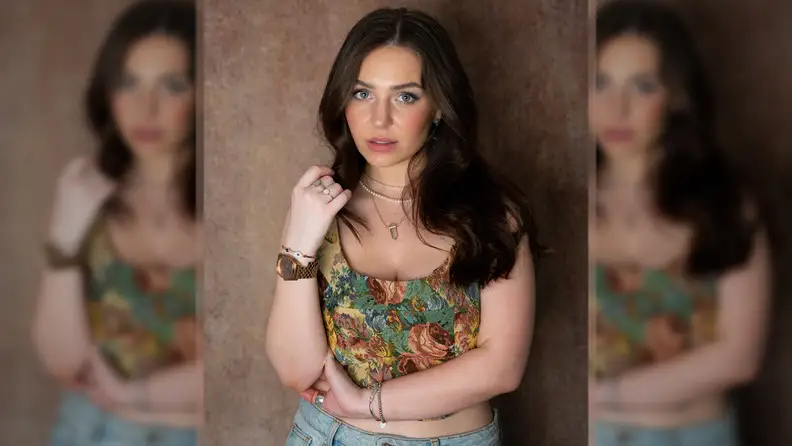 Actress and writer Bibi Lucille wearing a patterned corset, jeans, and layered necklaces, bracelets, and rings.