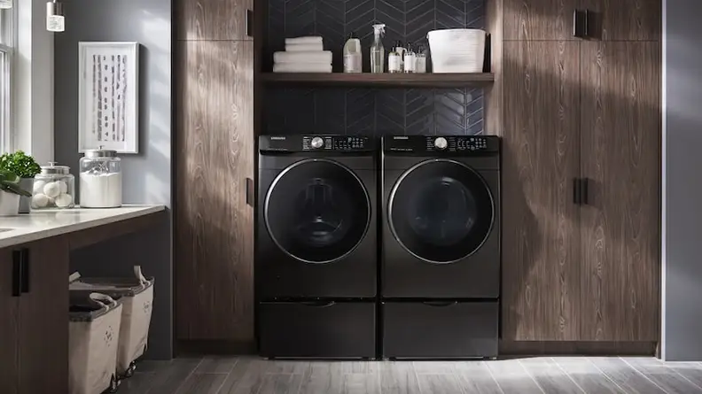 The Samsung DVE45R6300V standing besides a Samsung washer in a brown laundry room.