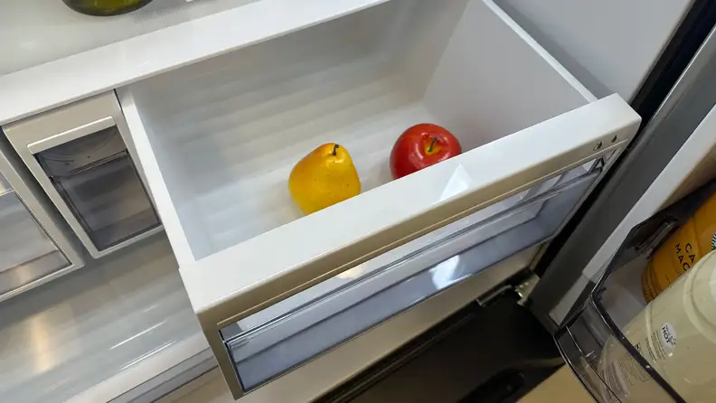 A close-up of a crisper drawer pulled out at a slight angle, showcasing how the side of the drawer can bump into its housing and create friction. It also shows how the drawer can hit the main door if it's not open the whole way.