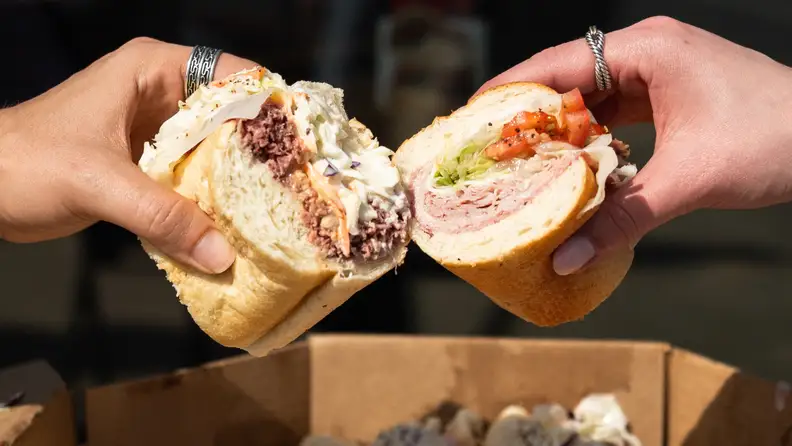 Hands holding a sandwich cut in half