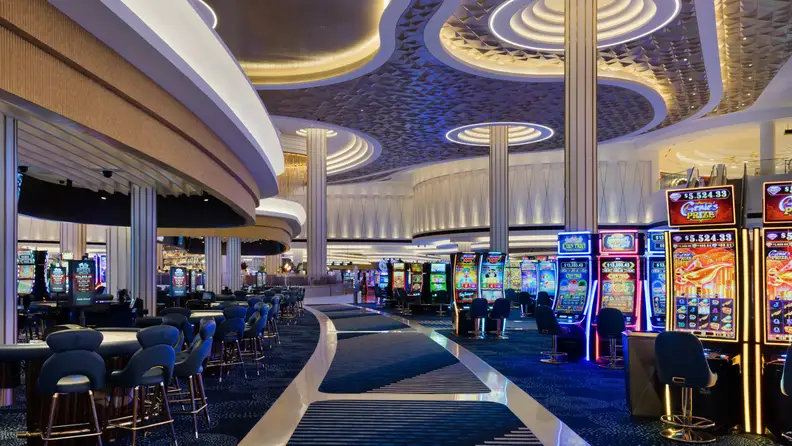 Fontainebleau Las Vegas casino floor featuring rows of slot machines, gaming tables, and a modern interior with dramatic curved ceilings and ambient lighting.