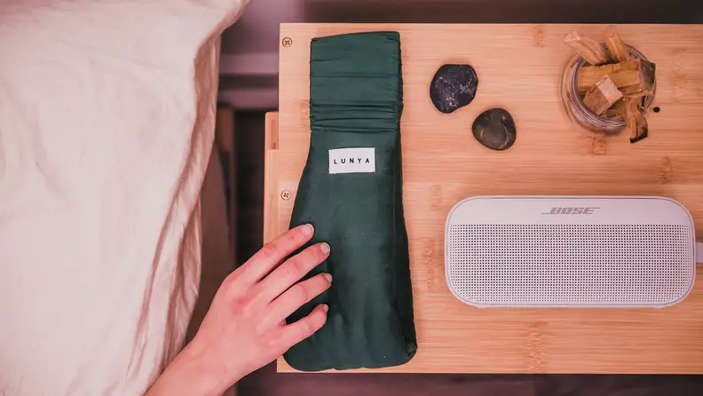 Eye mask rests on bedside table next to wireless speaker