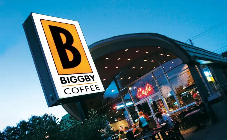 Illuminated storefront sign above a cafe at dusk
