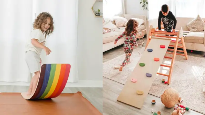 A child on a colorful wobble board and children on a play structure indoors