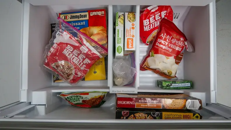 A close-up of the bottom bin of the Whirlpool freezer drawer. The main basin of the bin is divided by a tall, narrow bin, labeled with 