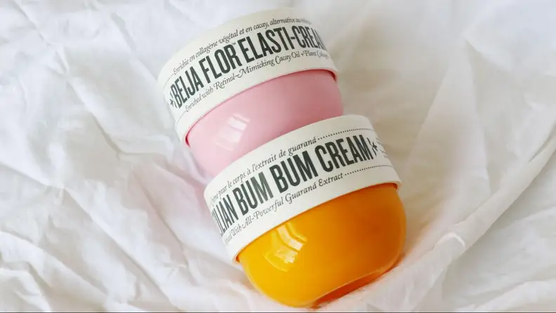 Two tubs of body lotion sit on a sheet.