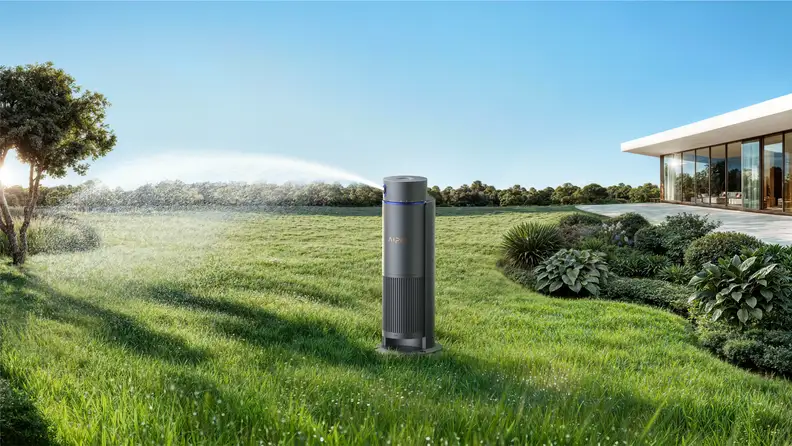 An Aiper IrriSense 2 smart outdoor sprinkler unit stands in the middle of a lush green lawn, actively watering the grass with a sweeping spray.