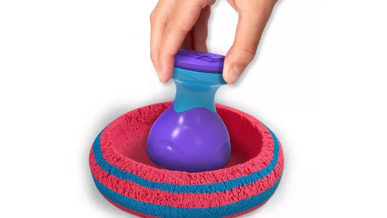 A hand plays with kinetic sand.