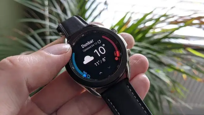 Person holding smart watch with fingers.