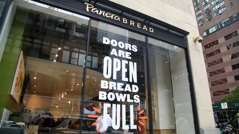Storefront window at Panera Bread with a sign reading "Doors Are Open, Bread Bowls Full."
