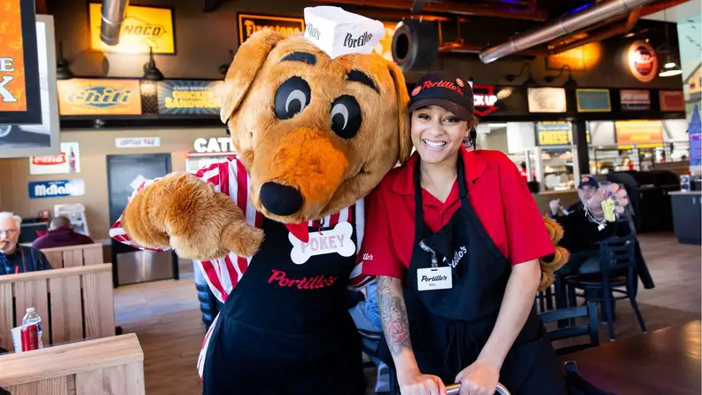Portillo's mascot Pokey posing with a smiling employee inside the restaurant