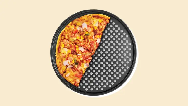 Half a pizza on a perforated tray on a beige background.