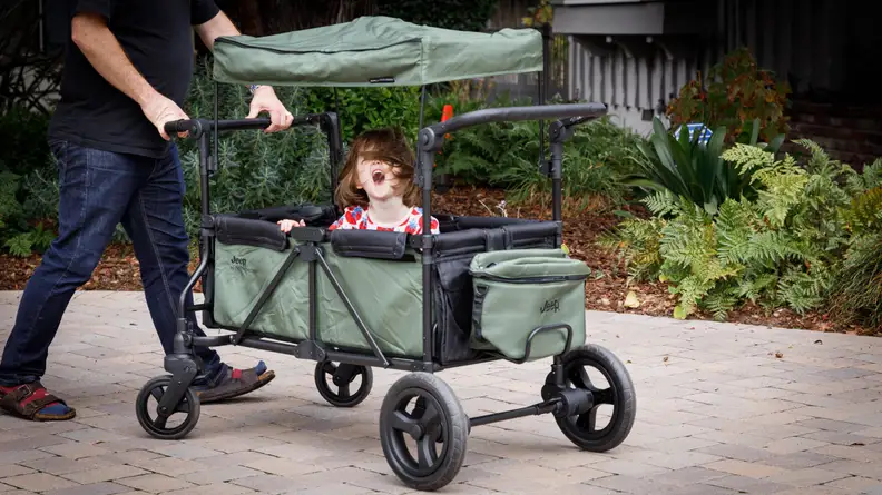 A man pushes a child in the Jeep stroller wagon.
