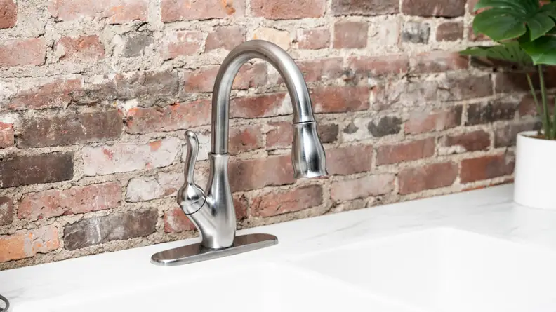 A silver faucet is attached to a white kitchen sink