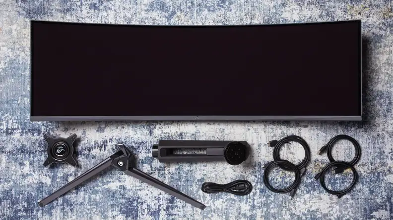 The Asus ROG Swift PG49WCD screen, stand, and cords laid out on a blue and white rug.