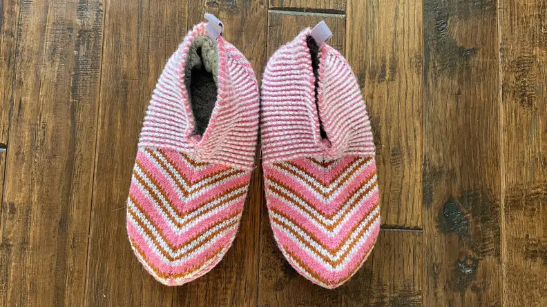Two pink Bombas gripper slippers on hardwood floor.