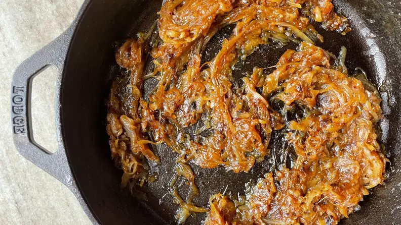 A cast-iron skillet filled with caramelized onions and shallots.