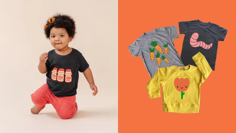 A little Black girl wearing a black shirt with milk cartons on it and red pants; on an orange background, three shirts are lying down. A grey t-shirt with smiling carrots, black t-shirt with pink worm who's smiling, and a yellow long sleeve shirt with an orange flower smiling