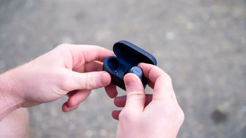 A person opens a case of earbuds.