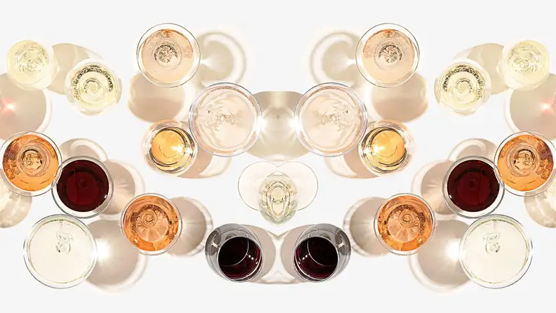 Shot from above, a spread of glasses of red, white, orange, and rosé wines on a white background.