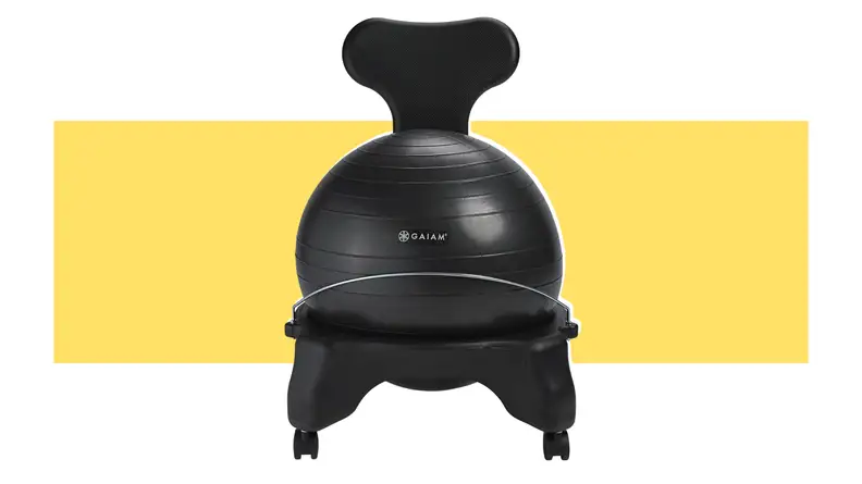 Black yoga ball sitting inside of black seat frame in front of yellow background.