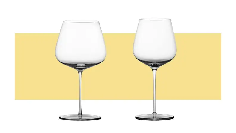 Two differently sized red wine glasses sit side by side on a yellow background.