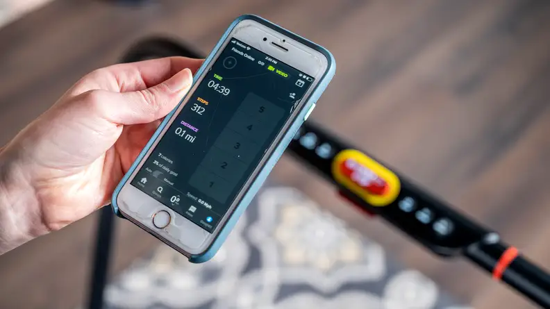 A hand holding a phone showing the Treadly app on the screen.