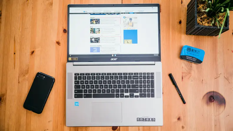 A laptop on a desk surrounded by several office supplies