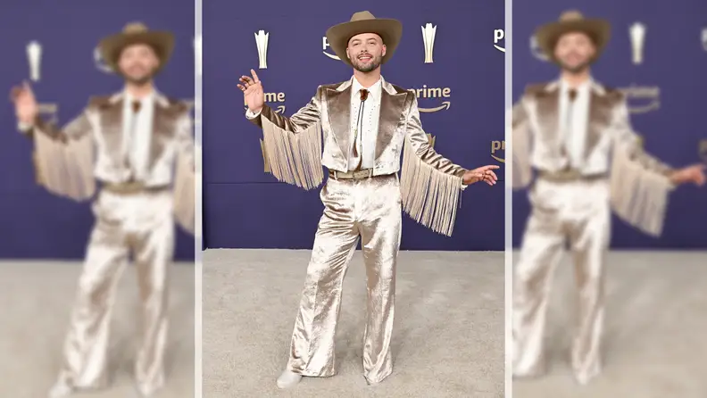 Country singer Adam Mac wearing a tan velvet suit with fringe details on the arms on the ACM red carpet.