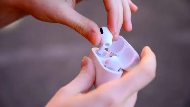 A person puts their headphones into a charging dock.