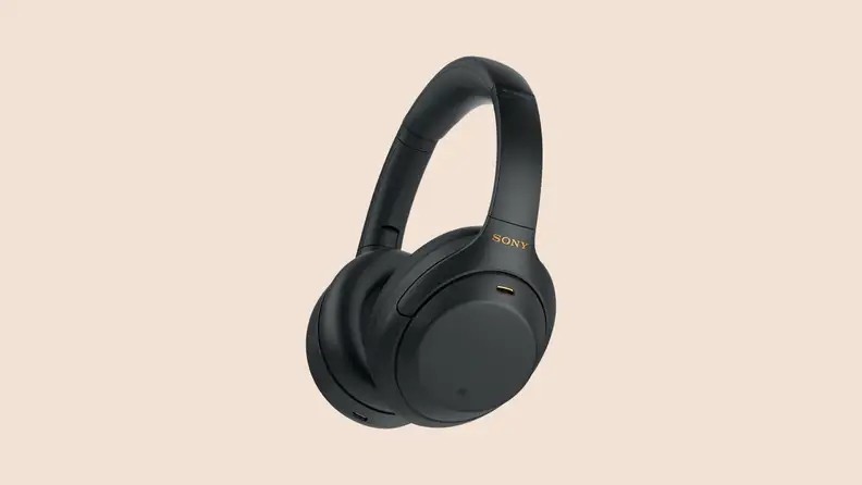 Angled view of the Sony WH-1000XM4 headphones in black on a beige background.