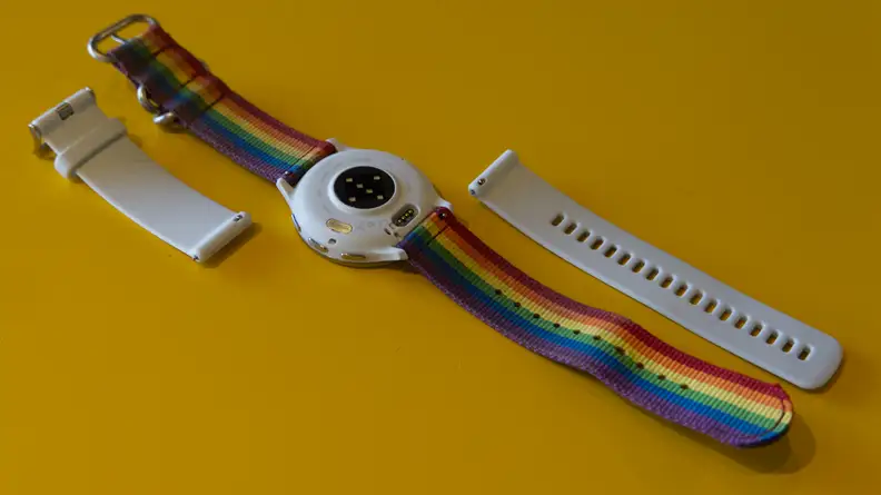 Garmin Venu 3 smartwatch with rainbow woven band next to detached white silicone band.