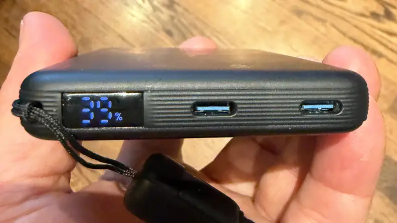Display battery percentage and USB-C ports on INIU SnapGo Air Power Bank, being held in a left hand.
