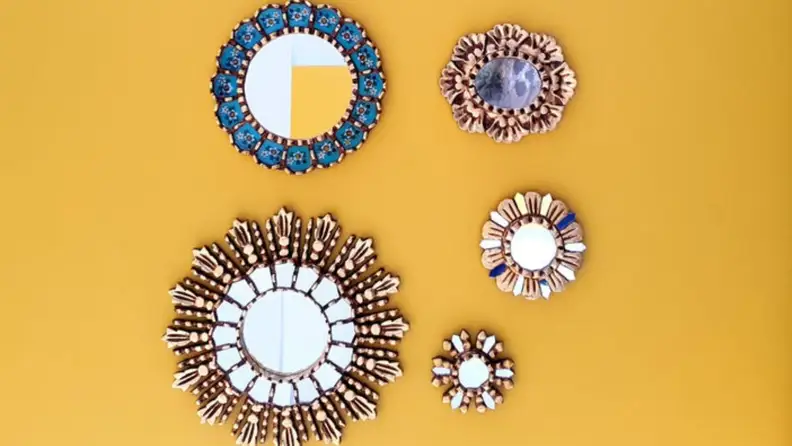 Set of five blue and gold gallery wall mirrors on a yellow wall