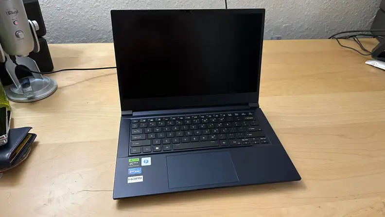 Origin EON14-S gaming laptop sitting on top of wooden surface with black screen display.