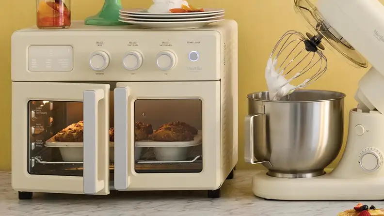 Cream-colored countertop oven and stand mixer displayed side by side while baking and mixing in a kitchen.